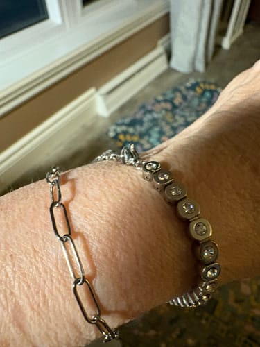 A customer's wrist wearing the thin paper clip chain bracelet stacked with another silver-toned bracelet.