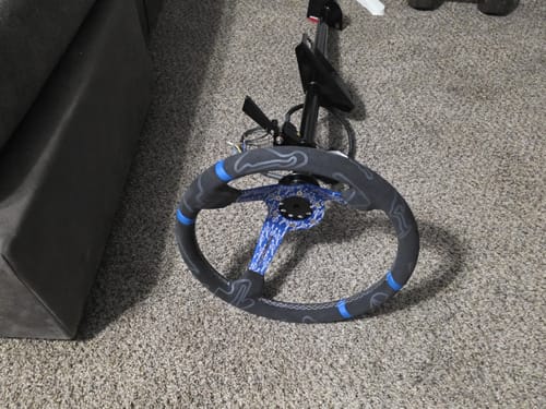 Customer's chromoly lightweight steering column with a custom wheel, shown on the floor before installation.