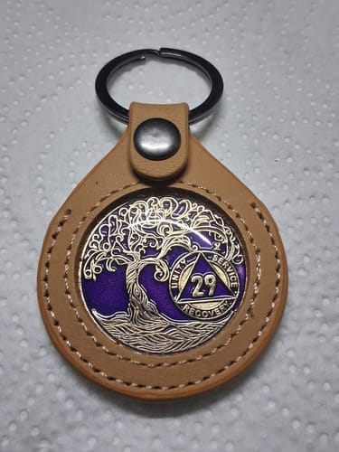 Reviewer's tan leather keychain holder displaying a Tree of Life recovery coin with a purple background.
