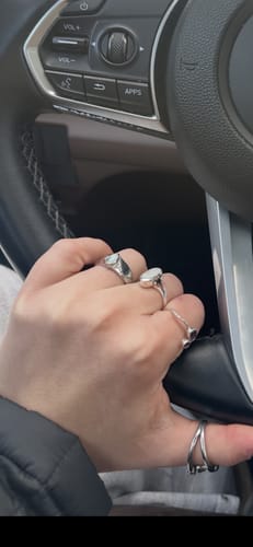 Customer wearing the October Birthstone Ring on their index finger while holding a car's steering wheel.
