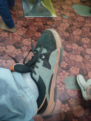 A reviewer's close-up view of their Bacca Bucci Groove Low Top Sneaker, showing the black and grey design with a thick gum sole.