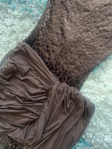 Close-up of the reviewer's brown Naked Ruched Drape Mini Skirt laid out on a textured rug.