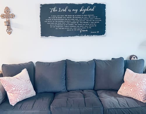 Reviewer's large Psalm 23 sign hanging on a wall above a dark sofa in a living room.