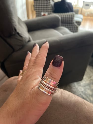 Customer's hand wearing the Two Tone Wide Band Spinner Ring on their thumb, showing the hammered texture.
