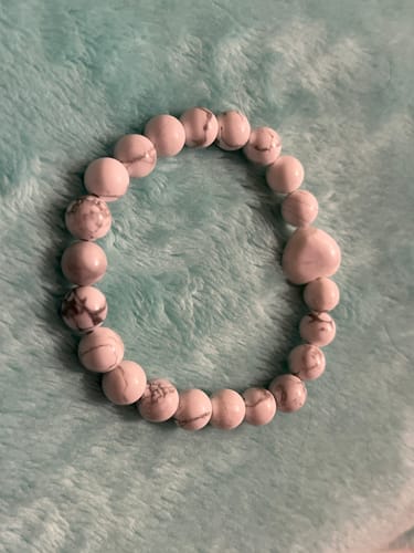 Customer's howlite bracelet with white marbled beads and a heart accent, on a fluffy blue surface.