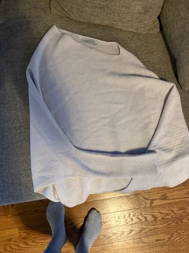 Reviewer's light beige Asymmetric Draped seamless knit top laid out on a couch.