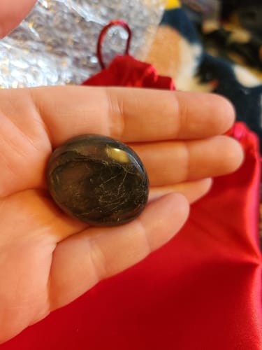 Customer holding the dark, polished monthly crystal in their palm, showing natural cracks.