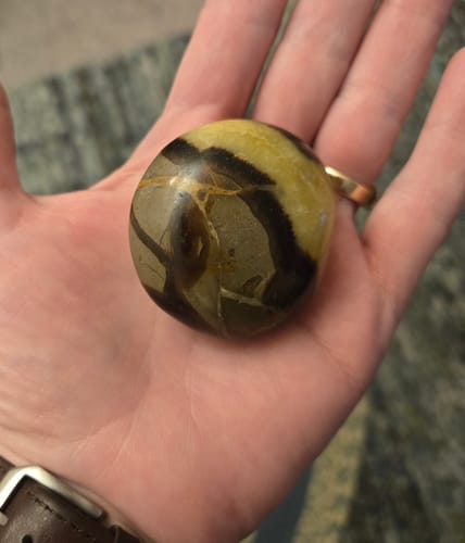 Reviewer holding the gorgeous striped palm stone from their monthly crystal subscription in their hand.