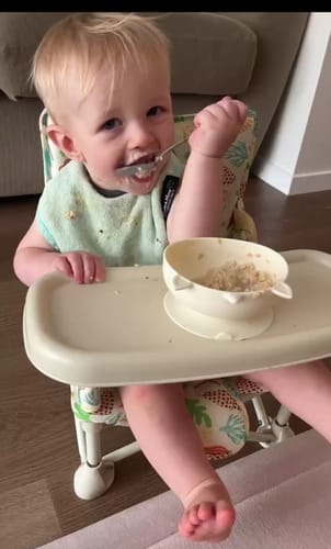 Customer's baby eating a meal in the patterned Sailor baby chair v2 with the attached tray.