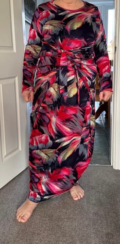 Reviewer wearing a long-sleeved wrap dress made from the colourful Feathered Garden jersey fabric.