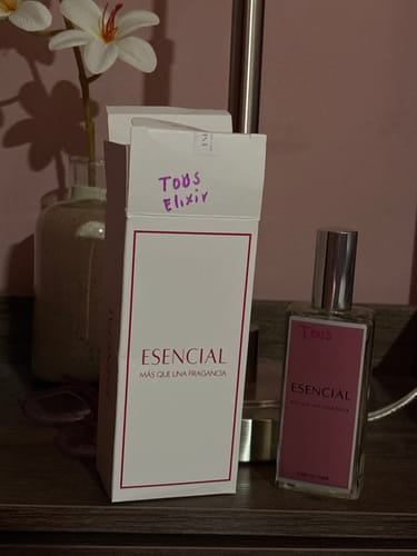 Cliente muestra la caja y el frasco del perfume Esencial M540 sobre un tocador.