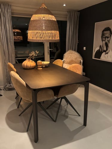 Klant toont de donkere Bronx71 Cala eettafel in een eetkamer, omringd door okergele stoelen.