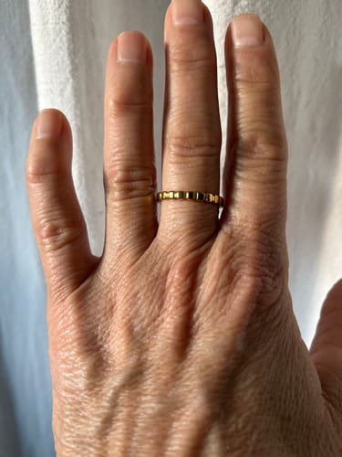 Reviewer's hand wearing the Callie Gold Band Ring, showing its simple segmented design.