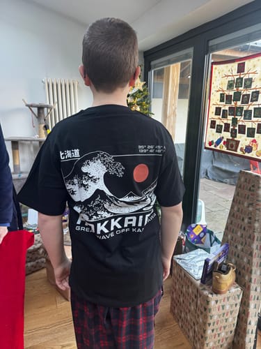 A customer seen from behind wearing the black Hokkaido Wave T-Shirt, showing the detailed graphic print.