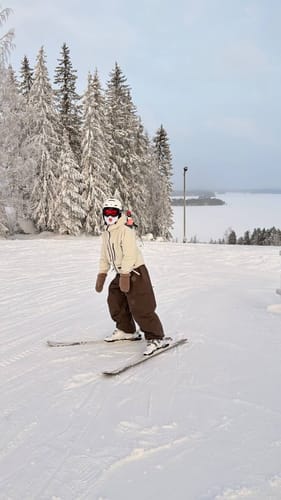 Reviewer skiing on a snowy slope wearing the coffee baggy waterproof snow pants.