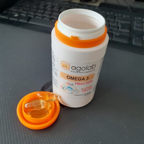 Cliente mostra il flacone di Omega 3 aperto con capsule dorate nel tappo arancione.
