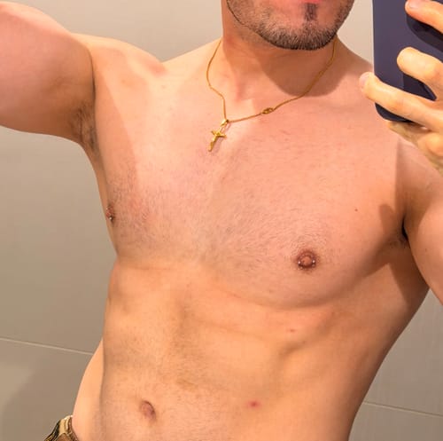 Un cliente muestra el colgante Cross Minimal Oro en su pecho en una selfie.
