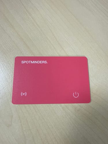 Customer's red SPOTMINDERS. Tracking Card lying flat on a light wood surface.