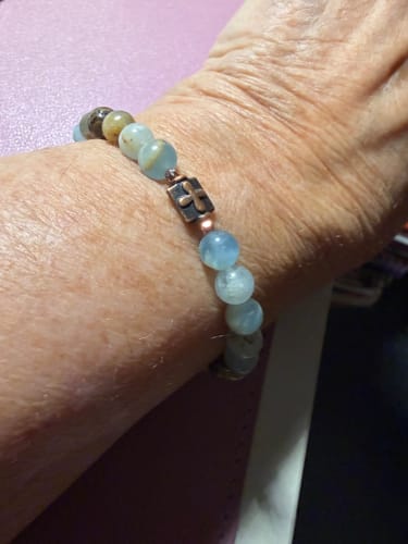 Close-up of a reviewer's wrist wearing the From Dawn to Dusk Bracelet with its blue calcite beads and copper cross.