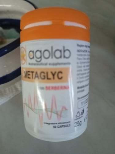 Recensore mostra la bottiglia bianca dell'integratore Agolab METAGLYC con il suo tappo arancione.
