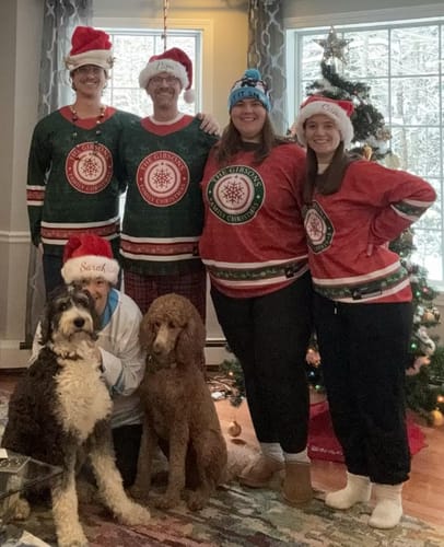 Customers posing in matching red and green Family Christmas Custom Hockey Jerseys by a Christmas tree.