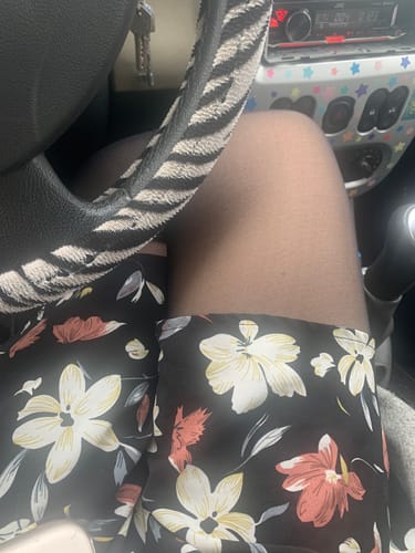 Gros plan sur une cliente portant les collants thermiques noirs sous un short à fleurs.