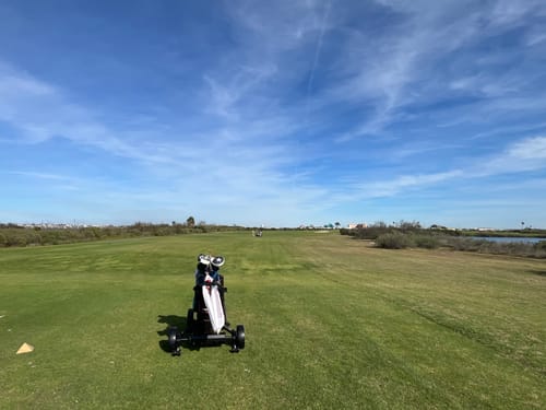Customer's Club Booster V2Pro attached to their golf cart on a wide fairway under a sunny blue sky.