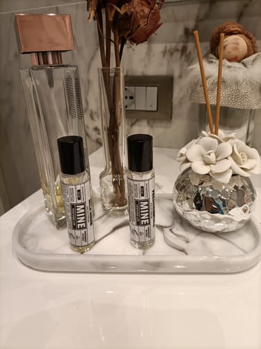 Recensore mostra due profumi MILK RHUM su un vassoio di marmo in bagno.