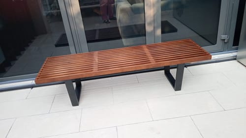 Customer's Retro Solid Wood Bench with a walnut slatted top and black legs, shown on a light tiled floor by a glass door.