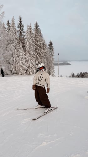 Reviewer on skis wearing the white Insulated Snow Jacket on a snowy slope.