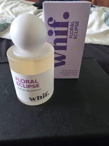 Customer's Floral Eclipse perfume bottle, with a frosted glass base and white spherical cap, next to its lavender box.