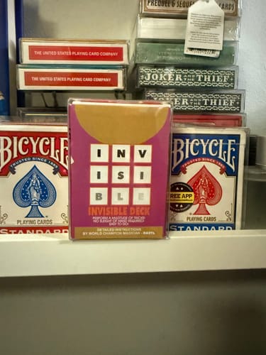 Reviewer's Invisible Deck box displayed on a shelf among other decks of playing cards.