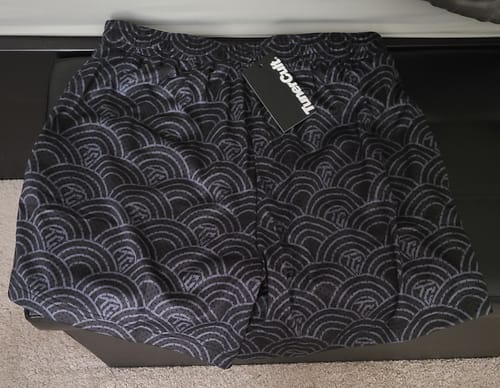 Customer's new APEX PREMIUM MESH SHORTS in black with a grey wave pattern, laid flat with the tag still on.