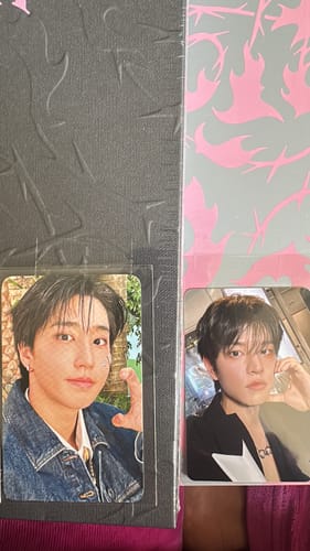 Reviewer's close-up of two photocards from the STRAY KIDS TAPE ALBUM, displayed on top of the album packaging.