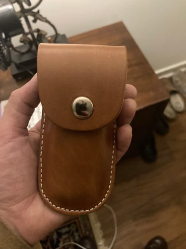 Reviewer holding the brown leather Canyon Utility Sheath, showing its white stitching and sturdy silver snap closure.