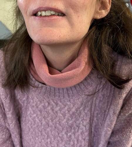 Close-up of a reviewer wearing the pink cashmere neckerchief for warmth.