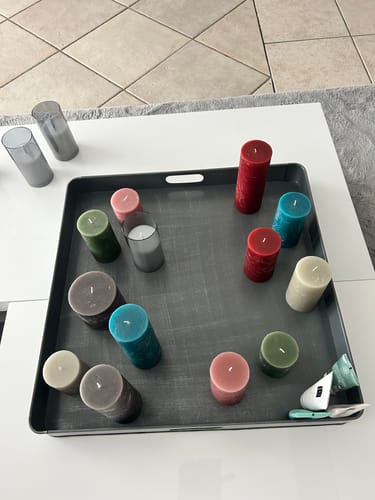 Recensent's grote, antiek grijze dienblad op een tafel, gedecoreerd met veel kaarsen.