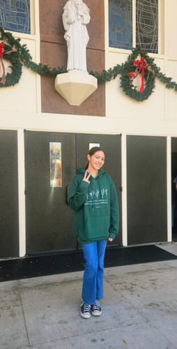Customer wearing the green Isaiah 40:8 Floral Forever Hoodie while posing in front of a church.