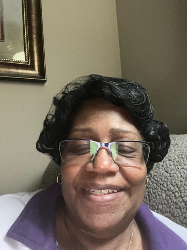 Customer smiling happily while wearing a short, dark wig with a curly style.