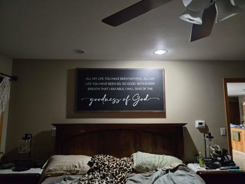 Customer's large black wall art with 'goodness of God' text displayed on a bedroom wall above a bed.