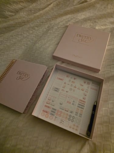 Reviewer's blush 2026 Signature Planner displayed with its keepsake box and an included sticker sheet.