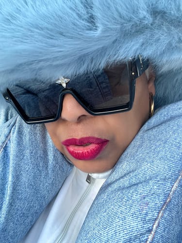 Close-up of a reviewer wearing the plush, blue Faux Fur Oversized Bucket Hat, styled with sunglasses and a denim jacket.