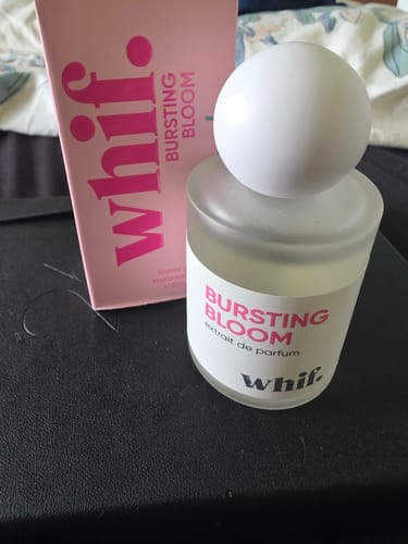 Customer's Whif Bursting Bloom perfume bottle with a white cap, shown next to its pink box on a dark surface.