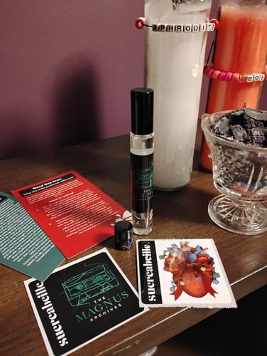 Customer's Jon and Martin fragrance spray on a wooden surface with included cards, stickers, and a sample.