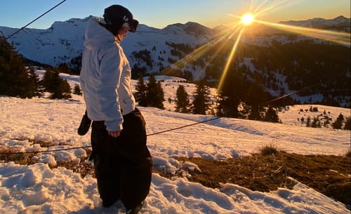 Reviewer wearing the baggy snow pants on a snowy mountain at sunset.