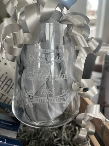 Ein Kunde zeigt das gravierte Leonardo Weinglas, das als Geschenk mit einer silbernen Schleife verziert ist.
