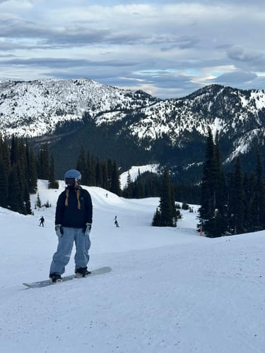 Reviewer on a snowboard wearing the baggy Denim Snow Pants on a snowy mountain slope.