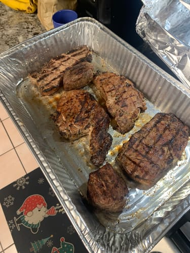 Customer's cooked steaks from the Choice Family Pack with nice grill marks resting in a foil pan.