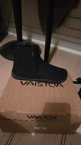 Arvostelijan musta Vaistoa Kajo -paljasjalkanilkkuri kenkälaatikon päällä.