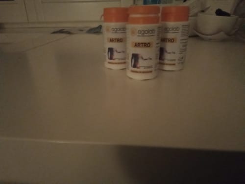 Cliente mostra tre flaconi di Artro con tappo arancione su un ripiano.